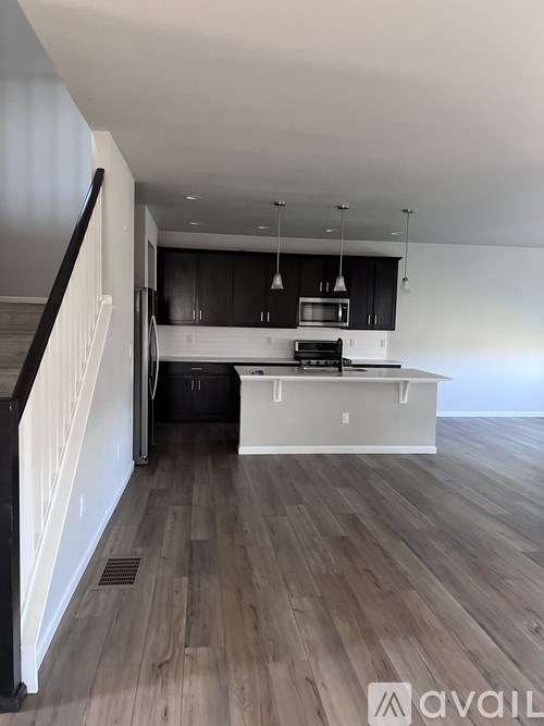 A modern kitchen with dark wood floors and white walls.