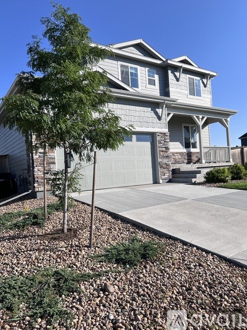 A house with a grey roof and a tree in front of it.