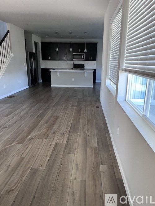 A spacious kitchen with wooden flooring and white walls.