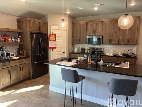 A kitchen with a black refrigerator and wooden cabinets.