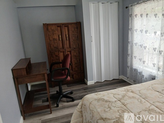 A bedroom with a bed, desk, chair, and a wardrobe.