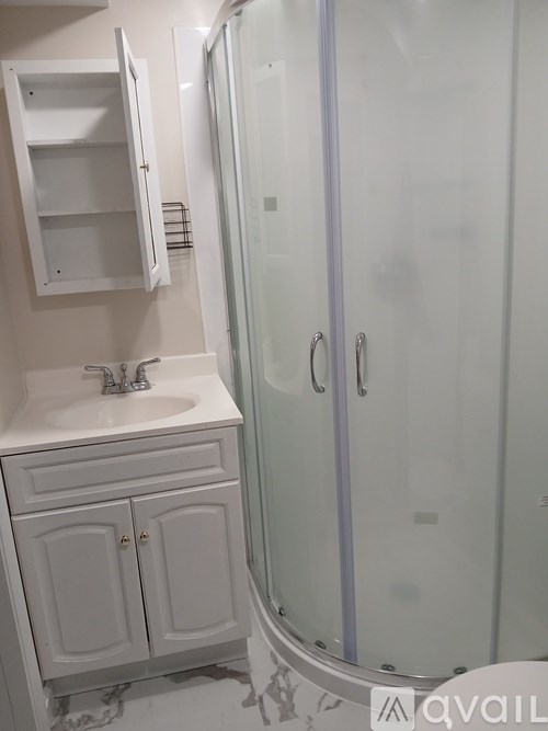 A white bathroom with a sink and a shower.