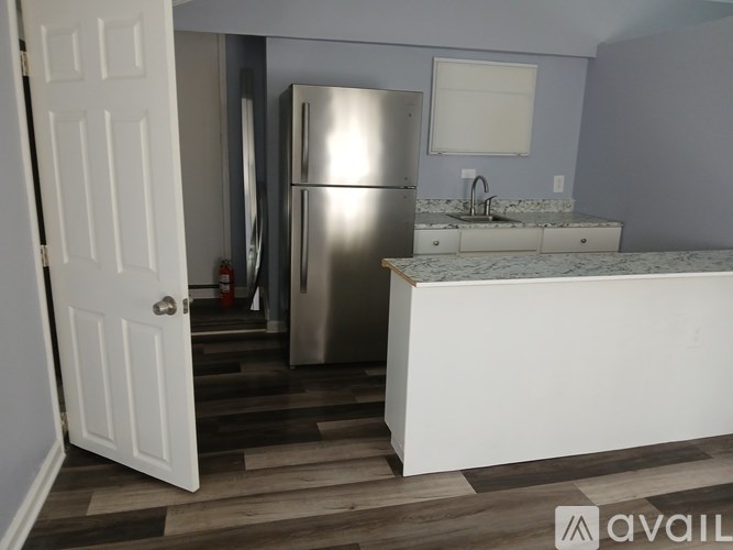 A kitchen with a refrigerator, sink, and wooden floors.