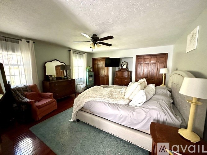 A bedroom with a large bed and a ceiling fan.