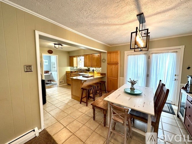 A kitchen with a table and chairs in the foreground and a counter with a sink in the background.