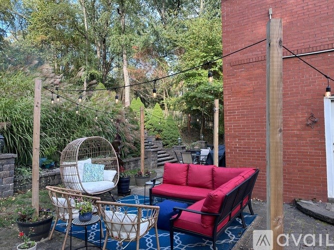 A patio with a red couch and a hanging chair.