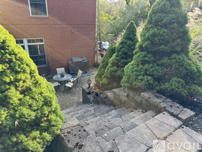 A stone staircase leads up to a patio with a table and chairs.