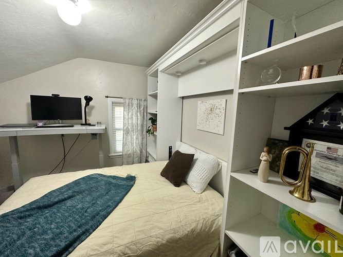 A bedroom with a bed, a TV, and a shelf with various items.