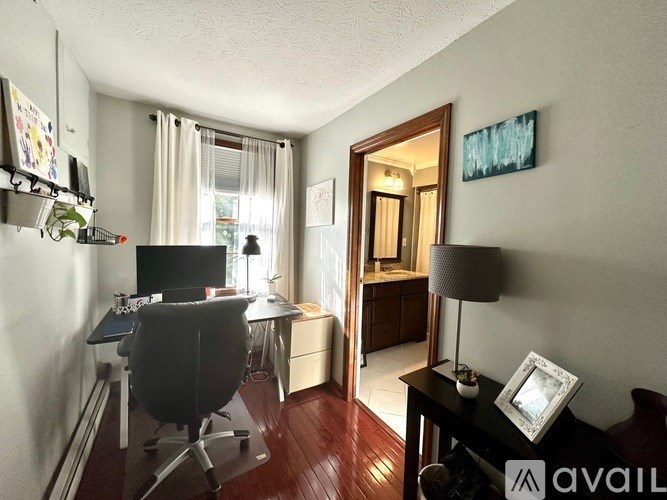 A room with a desk, chair, and a lamp.