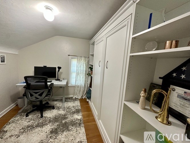 A room with a black chair and a black desk with a computer on it.