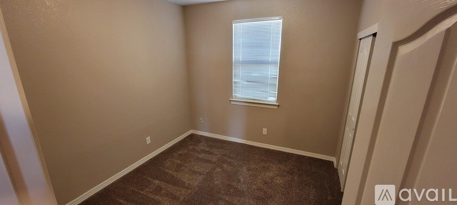 A room with a carpeted floor and a window with blinds.
