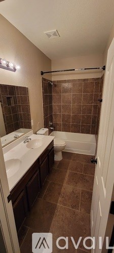 A bathroom with brown tiles and a white toilet.