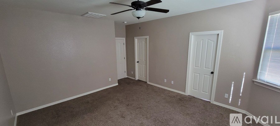 A room with a ceiling fan and two doors.