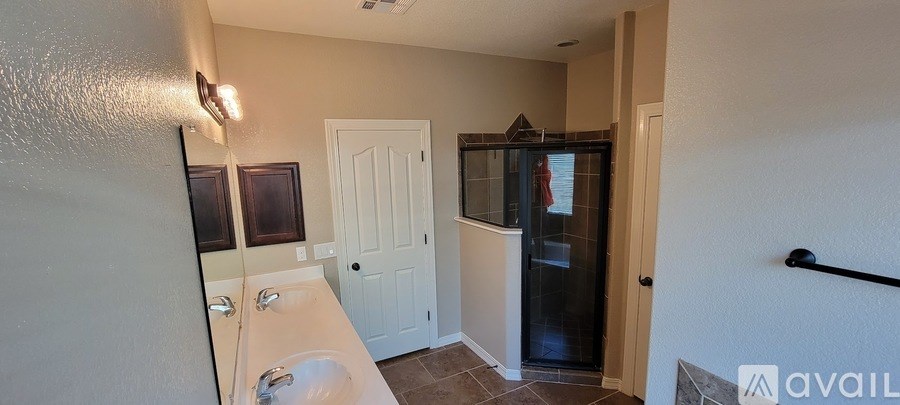 A bathroom with a sink, mirror, and a shower stall.