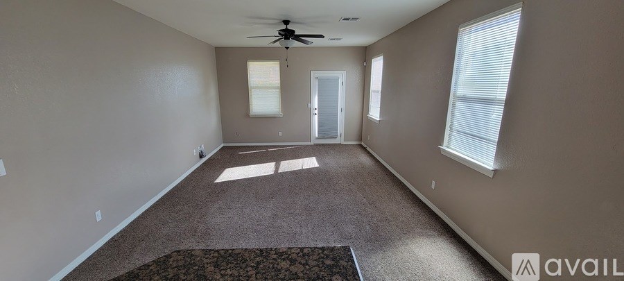 A spacious room with a carpeted floor and a ceiling fan.