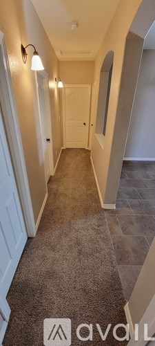 A hallway with a carpeted floor and white walls.