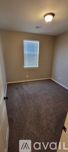 A room with a carpeted floor and a window with blinds.