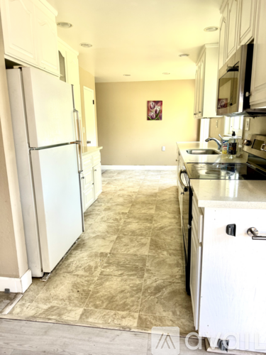 A kitchen with a refrigerator and a sink.