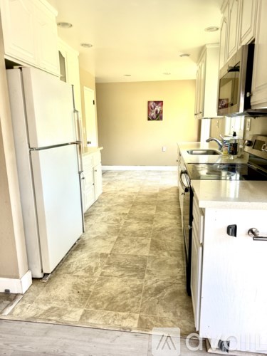 A kitchen with a refrigerator and a sink.