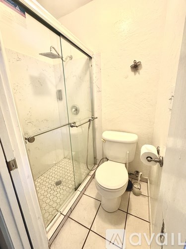 A white toilet with a glass shower stall in a bathroom.