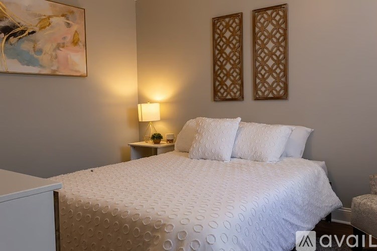 A bedroom with a large bed and two wall lamps.