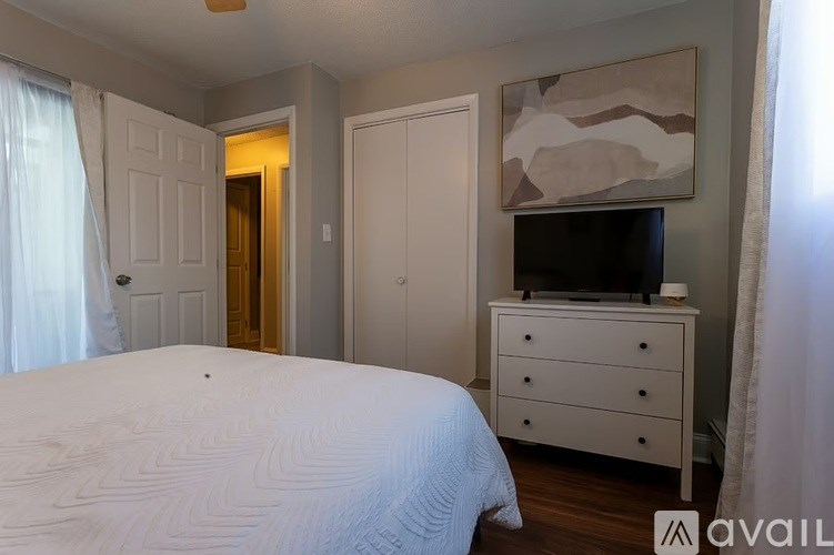 A bedroom with a large bed, a dresser, and a television.
