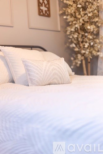A white bed with a pillow and a white bedspread.