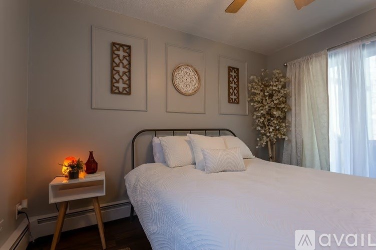 A bedroom with a bed, a table with a vase, and three wall hangings.