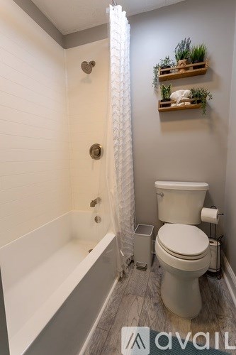 A white toilet in a bathroom with a white shower curtain.