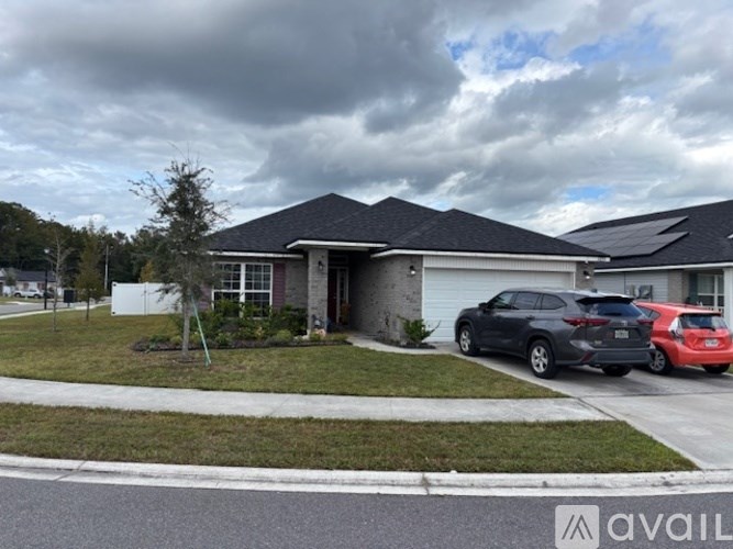 A house with a grey roof and a red car parked in front.