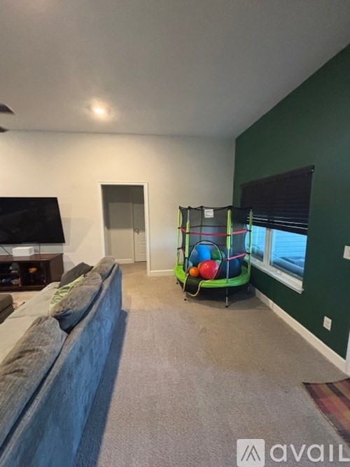 A living room with a grey couch and a green playpen.