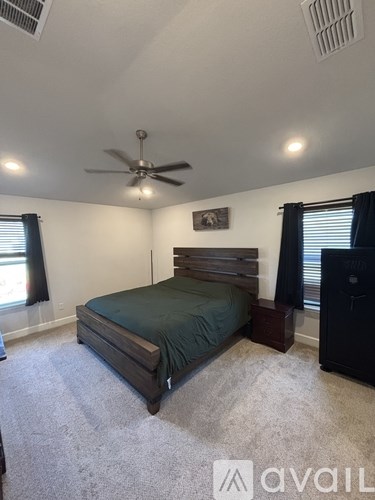 A bedroom with a bed, dresser, and ceiling fan.