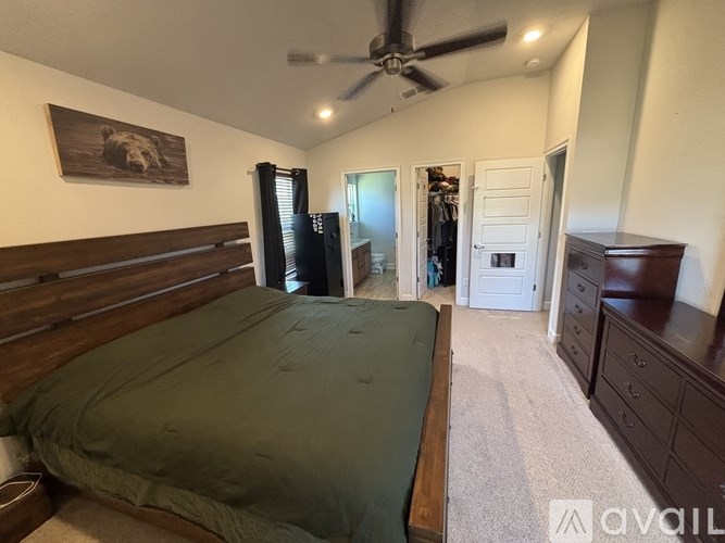 A bedroom with a bed, dresser, and a ceiling fan.