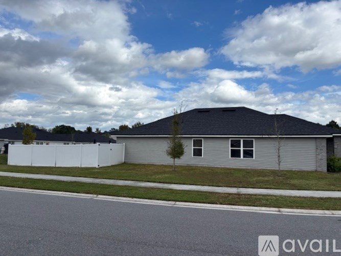 A house with a grey roof and a white fence is available for sale.