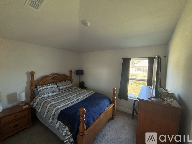 A bedroom with a bed, nightstand, and window.