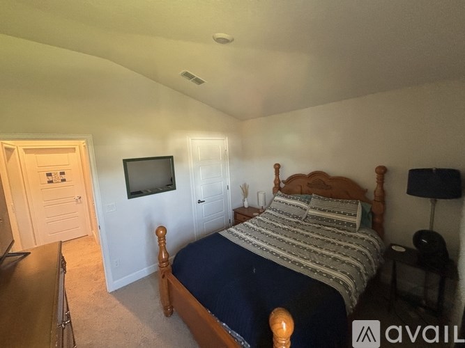 A bedroom with a bed, dresser, and television.