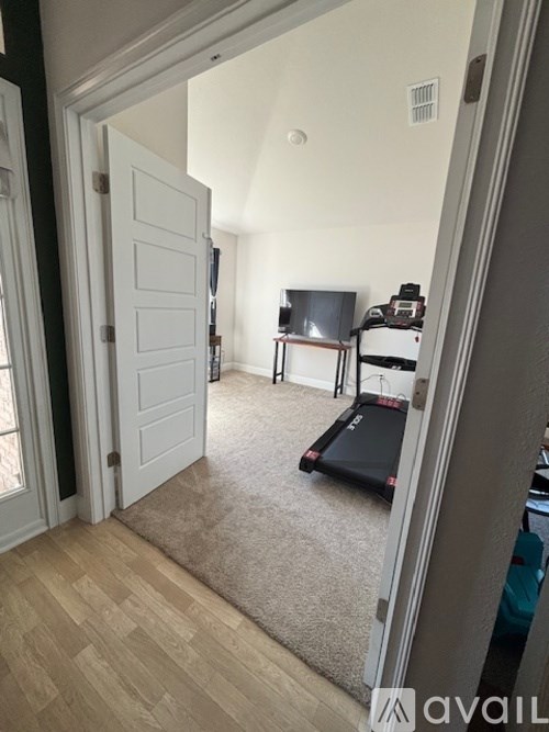 A room with a treadmill, a table, and a chair.