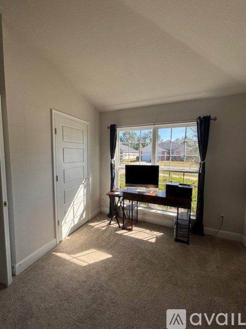 A room with a table and chairs by a window.