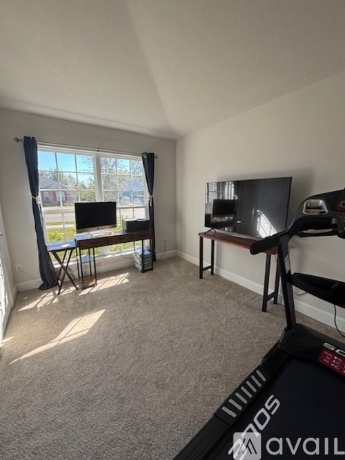 A room with a treadmill, a table, and a TV.