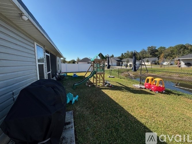 A backyard with a slide, trampoline, and a red wagon.
