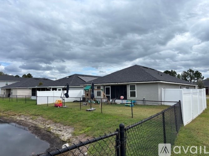 A house with a grey roof and a black fence in front of it.