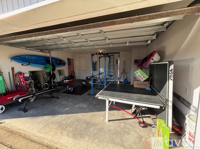 A garage with a surfboard, weights, and a bench.