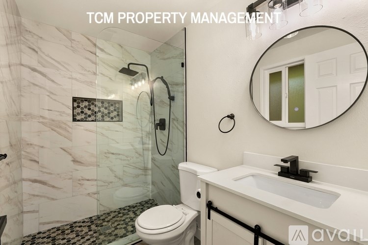 A bathroom with a marble wall and a round mirror.