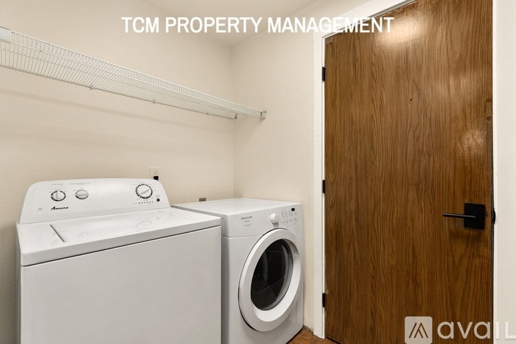 A laundry room with a washer and dryer, managed by TCM Property Management.
