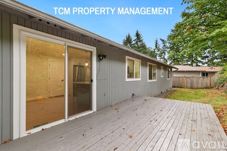 A wooden deck is in front of a grey building with the words "TCM PROPERTY MANAGEMENT" written above it.
