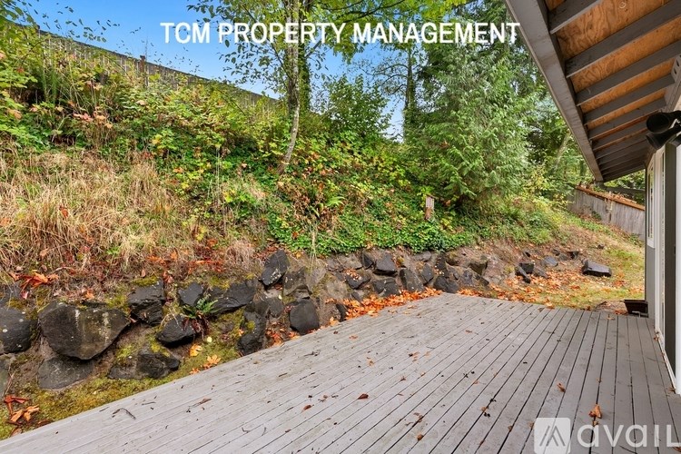 A wooden deck leads to a lush green hillside.