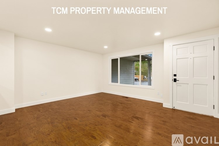 A room with wooden flooring and white walls, managed by TCM Property Management.