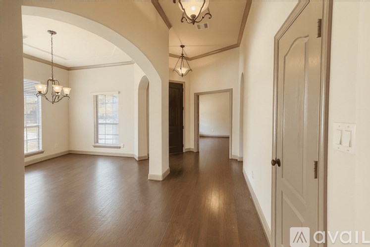 A spacious room with wooden floors and a chandelier.