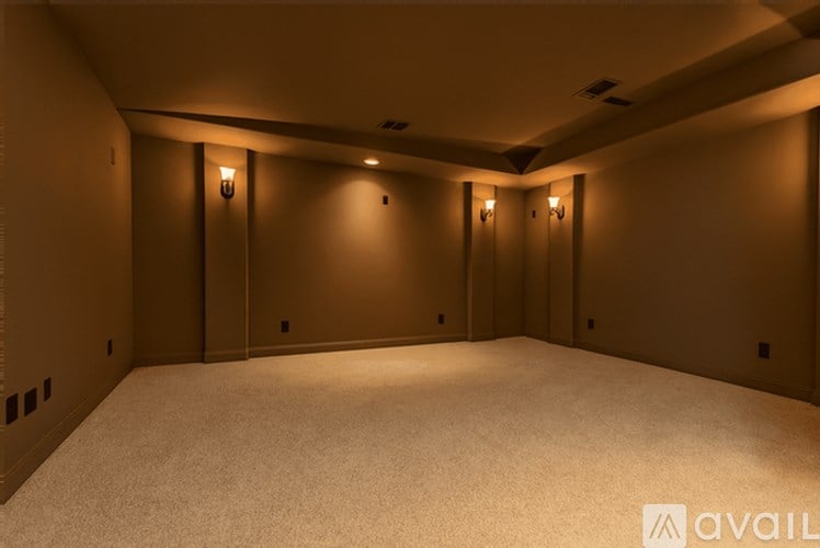 A spacious room with carpeted floor and wall-mounted lights.