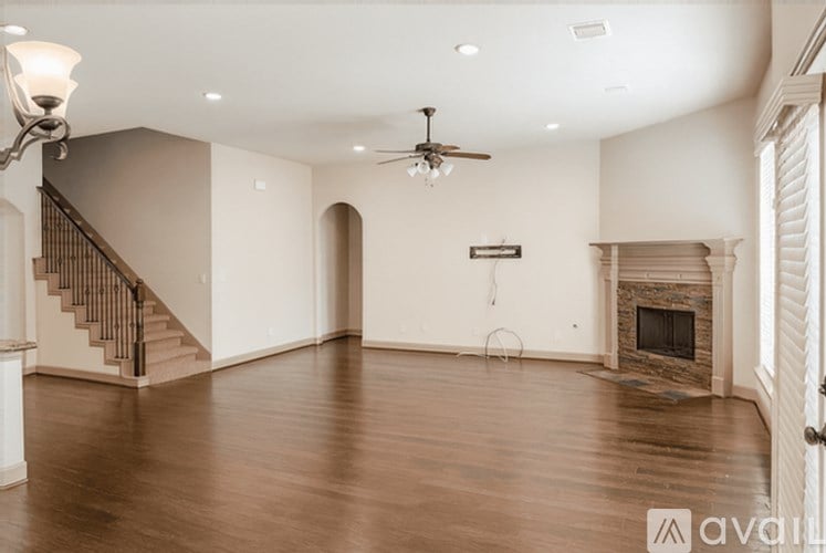 A spacious living room with a fireplace and a ceiling fan.